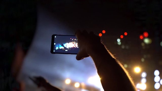 Fans are filming a concert on a smartphone. Live broadcast of the concert in social networks. People make photos and videos at the festival. World tour of popular musicians
