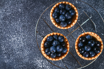 Blue blackthorn berries in sand tartlets on a table.
