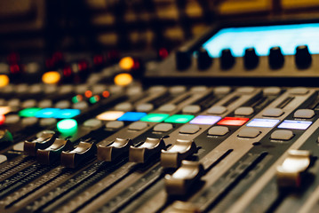 a professional concert mixing console with faders is used by a DJ for recording music. Close-up