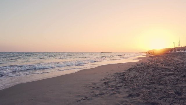 Orange sunset/sunrise or golden hour on a sandy beach in Costa dorada, Spain. Mediterranean sea waves in Altafulla, Spain.