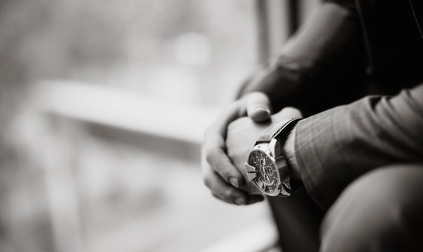 black and white photo of a businessman in a suit with a watch on his hand. Blurred background. Close-up