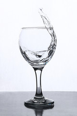 A splash of water in a wineglass on a white background.