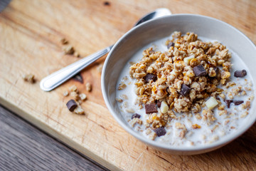 Bowl of chocolate muesli and milk on dark background