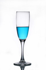 Blue liquid in a champagne glass on a white background.