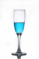 Blue liquid in a champagne glass on a white background.