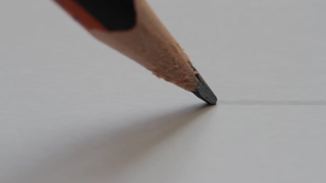 pencil draws a line on paper, close-up
