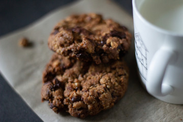 Delicious chocolate chip cookies and cup of milk on dark background
