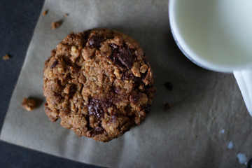 Delicious chocolate chip cookies and cup of milk on dark background