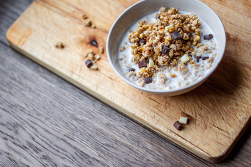 Bowl of chocolate muesli and milk on dark background