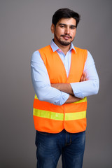 Fototapeta premium Young handsome bearded Persian man construction worker against g