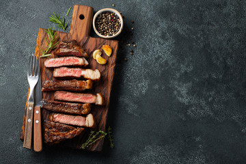 Sliced steak Striploin, grilled with pepper, garlic, salt and thyme served on a wooden chopping...