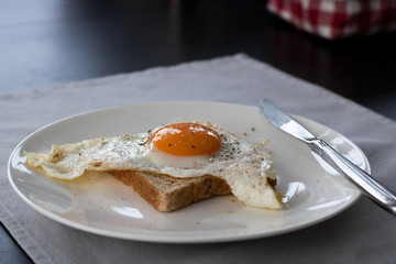 A fried egg with toast on a white plate
