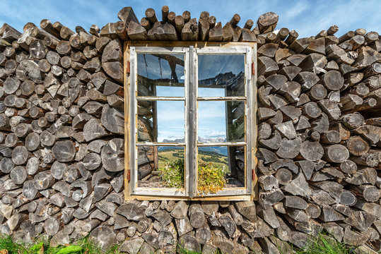 Fototapeta firewood stacked with a window in the center with flowers
