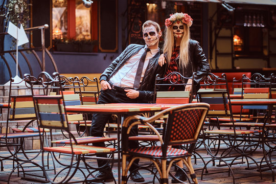 Young attractive couple with undead posing near mexican restaurant outdoors.