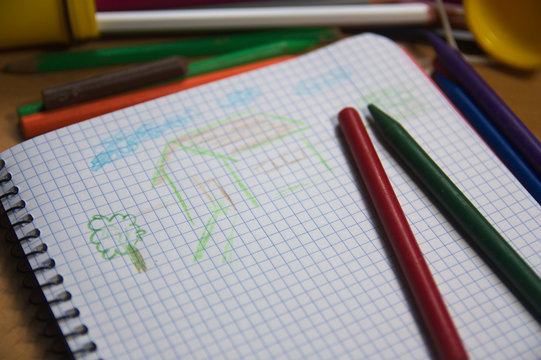 A school notebook where a child has drawn a simple house