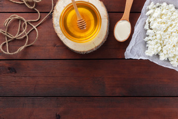 Dairy products on wooden boards. Cottage cheese and cream. Soft cheese and honey on wooden background. Cottage cheese on parchment paper. Twine next to dairy products. Honey on wooden stand
