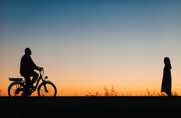 Fototapeta premium Male cyclist on the e-bike or electric bicycle on the sunset background. Silhouette of the man in profile. Active pension. Travel. Sport.