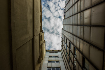 narrow south country street from below foreshortening and view on frame of buildings and blue contrast sky with clouds