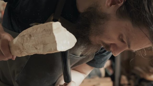 Skilled craftsman carpenter saws a workpiece of wooden board with a jig saw in a workshop. Making handmade furniture.