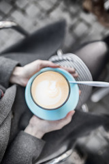 Female hands holding a turquoise cup of coffee latte
