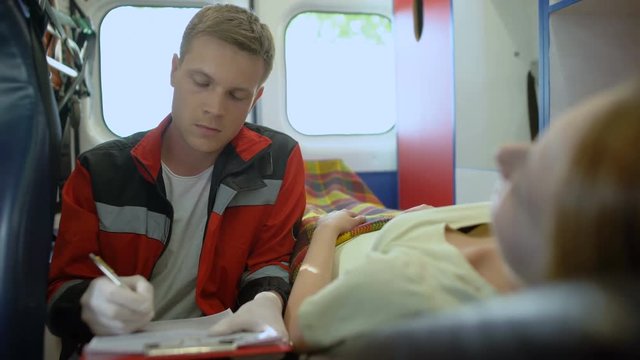 Doctor asking patient questions and filling out medical form in ambulance