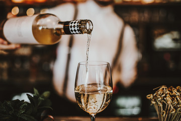 Close up shot of a bartender pouring white wine into a glass. Hospitality, beverage and wine...