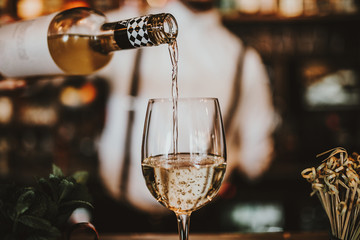 Close up shot of a bartender pouring white wine into a glass. Hospitality, beverage and wine...