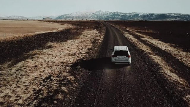 Epic aerial shot of white SUV driving through amazing landscape in Iceland