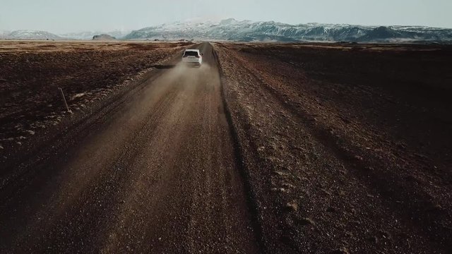 Epic aerial shot of white SUV driving through amazing landscape in Iceland