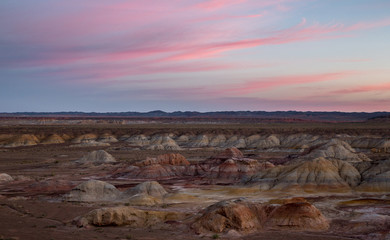 Fototapeta na wymiar Rainbow Hills in China. Rainbow City, Wucai Cheng. Colorful layered landforms in a remote desert area of Fuyun County. Uygur Autonomous Region, Xinjiang Province. Sunrise - Pink, Purple and Blue Sky