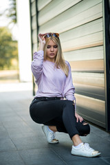 Photographing a girl during autumn near a high-tech glass building with a blurred background of the park