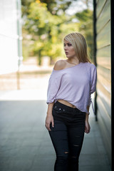 Photographing a girl during autumn near a high-tech glass building with a blurred background of the park