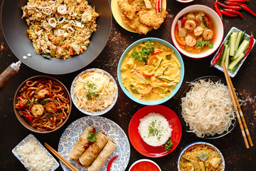 Asian oriental food composition in colorful dishware, served on dark rustic background, top view. Chinese, vietnamese, thai cuisine set. With copy space.