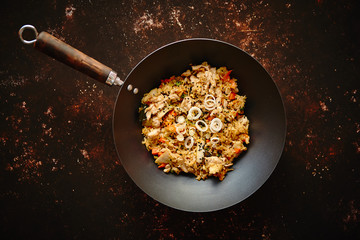Traditional orginal fried spicy rice with chicken served in a round iron wok. Placed on rusty dark...