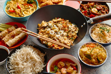 Chinese food set. Chinese noodles, fried rice with chicken, tom yum soup, spring rolls, deep fried fish and udon. Top view. Asian style food concept composition.