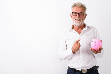 Studio shot of happy senior bearded man smiling while holding pi