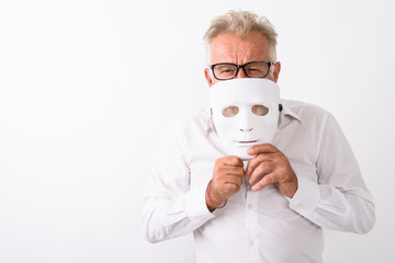 Studio shot of handsome senior bearded man covering mouth with w