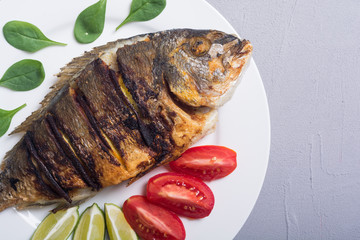 Fried fish dorado with lime , tomatoes and spinach