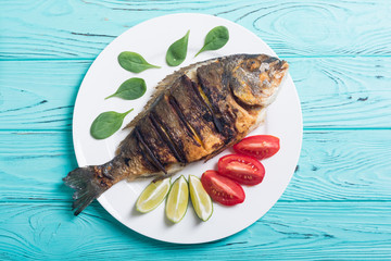 Fried fish dorado with lime , tomatoes and spinach
