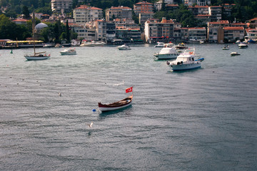 View of motorboats and yachts, buildings on European side and Bosphorus in Istanbul. It is a sunny summer day.