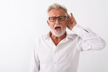 Studio shot of handsome senior bearded man listening while weari