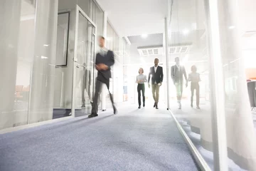 Foto op Plexiglas Blurred motion of modern business people crossing illuminated office corridor while hurrying to their workplaces, corporate company © Seventyfour