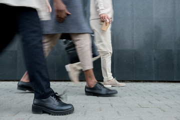 Naklejka premium Close-up of unrecognizable fashionable modern business people walking over city street while going to office, lifestyle concept