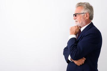 Profile view of handsome senior bearded businessman thinking whi