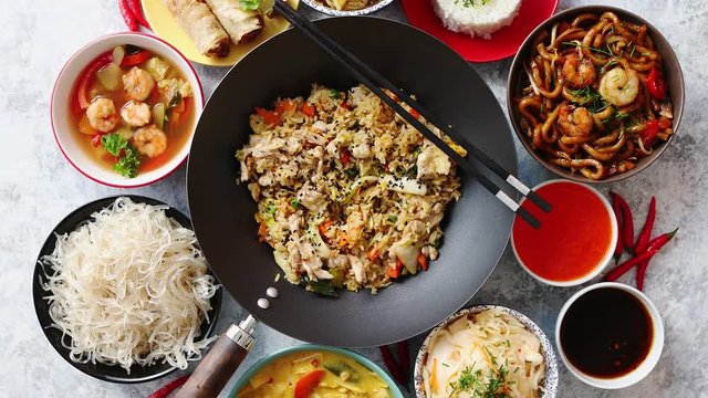 Chinese food set. Chinese noodles, fried rice with chicken, tom yum soup, spring rolls, deep fried fish and udon. Top view. Asian style food concept composition.