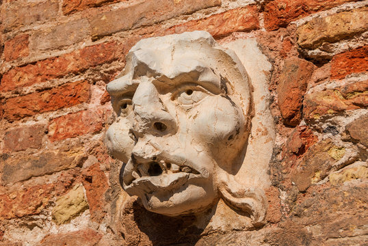 Frightening demon face old relief on wall in Venice