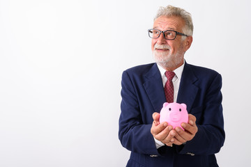 Studio shot of happy senior bearded businessman smiling while th