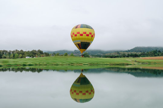 Beautiful Landscape With High Mountain , Reflection In Mountain Lake, Blue Sky And Big Yellow Ballon. Singha Park, Chiang Rai, North Of Thailand