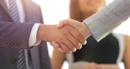 Businesspeople  shaking hands against room with large window loo