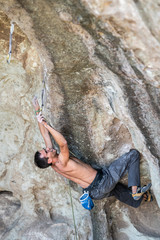 The last movements to reach the summit by a male climber. Rock climbing inside the Andes mountains at Cajon del Maipo, Chile. Climber solving the movements of 